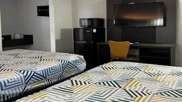A hotel room with two beds, a television, a refrigerator, and a desk.