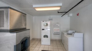 A laundry room with a washing machine, dryer, and a sign indicating soap and bleach softeners. - Cozy 1 Queen Bed | Mini Fridge (Bradenton)