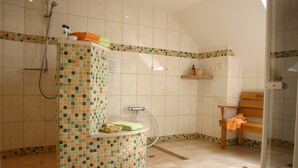 Un baño con ducha, un banco y una pequeña mesa de madera.