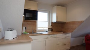 Una kitchenette compacta con microondas, tostadora, fregadero y armarios.