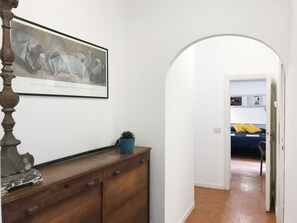 A hallway with a wooden dresser, a framed artwork, and a potted plant. - Casa Marina (Roma)