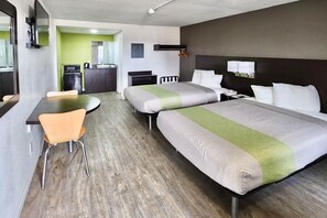 A hotel room with a bed, a desk, a chair, a kitchenette, and a bathroom.