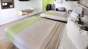 A hotel room with a bed, a desk, a chair, a television, and a green wall.