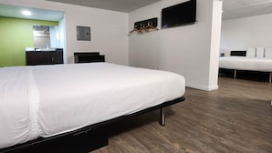 A hotel room with a bed, a TV mounted on the wall, and a wooden floor. - 1 King Bed | Suite, Non-Smoking, Micfridge (Columbus)