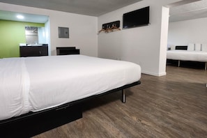 Habitació d'hotel amb un llit, un televisor fixat a la paret i un terra de fusta.