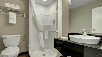 A bathroom with a toilet, a shower enclosure, and a sink with a mirror.