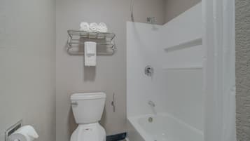 A bathroom with a toilet, a shower, and a towel rack with towels.