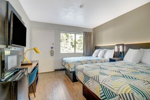 A hotel room with a bed, a desk with a television, a lamp, and a window with curtains. - 2 Full Beds | Non-Smoking, Micfridge (Venice)