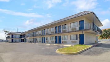 Een motel met een gebouw van twee verdiepingen, meerdere kamers en een parkeerplaats.