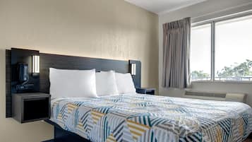 A hotel room with a bed, bedside tables, a phone, and a window with curtains.