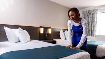Ein Hotelzimmer mit zwei Betten, einem Nachttisch mit Telefon und einer Wandleuchte.
