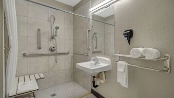 A modern bathroom with a walk-in shower, grab bars, a sink, and a towel rack.