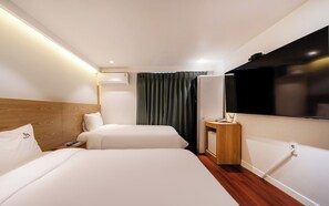 A hotel room with two beds, a flat-screen TV, a bedside table with a phone, and a wall-mounted air conditioning unit. - Busan Suyeong Bomnal (Busan)