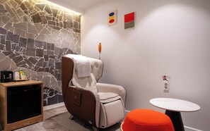 A modern room with a massage chair, a small table, and a wall with a mosaic design. - Busan Suyeong Bomnal (Busan)