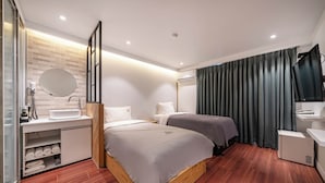 A modern hotel room with a wooden floor, a large bed, a bedside table, a mirror, a built-in TV, and a window with curtains. - Busan Suyeong Bomnal (Busan)