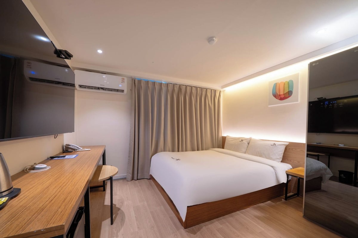 A hotel room with a bed, a desk, a television, and a minibar.