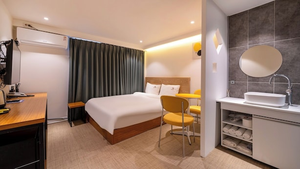 A hotel room with a bed, a desk, a chair, a bathroom with a sink and mirror, and a wardrobe. - Busan Suyeong Bomnal (Busan)