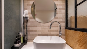 A bathroom with a white sink, a round mirror, and a hairdryer on the wall. - Busan Suyeong Bomnal (Busan)
