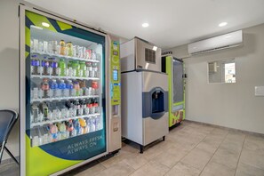 Ein Getränkeautomat mit verschiedenen Getränken und ein Wasserspender in einem sauberen, gut beleuchteten Raum mit gefliestem Boden.