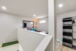 Un interior moderno con una escalera blanca, un espejo, un ventanal pequeño y un mueble para guardar ropa.
