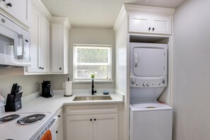Cocina compacta equipada con microondas, estufa, pileta y lavadora y secadora superpuestas.