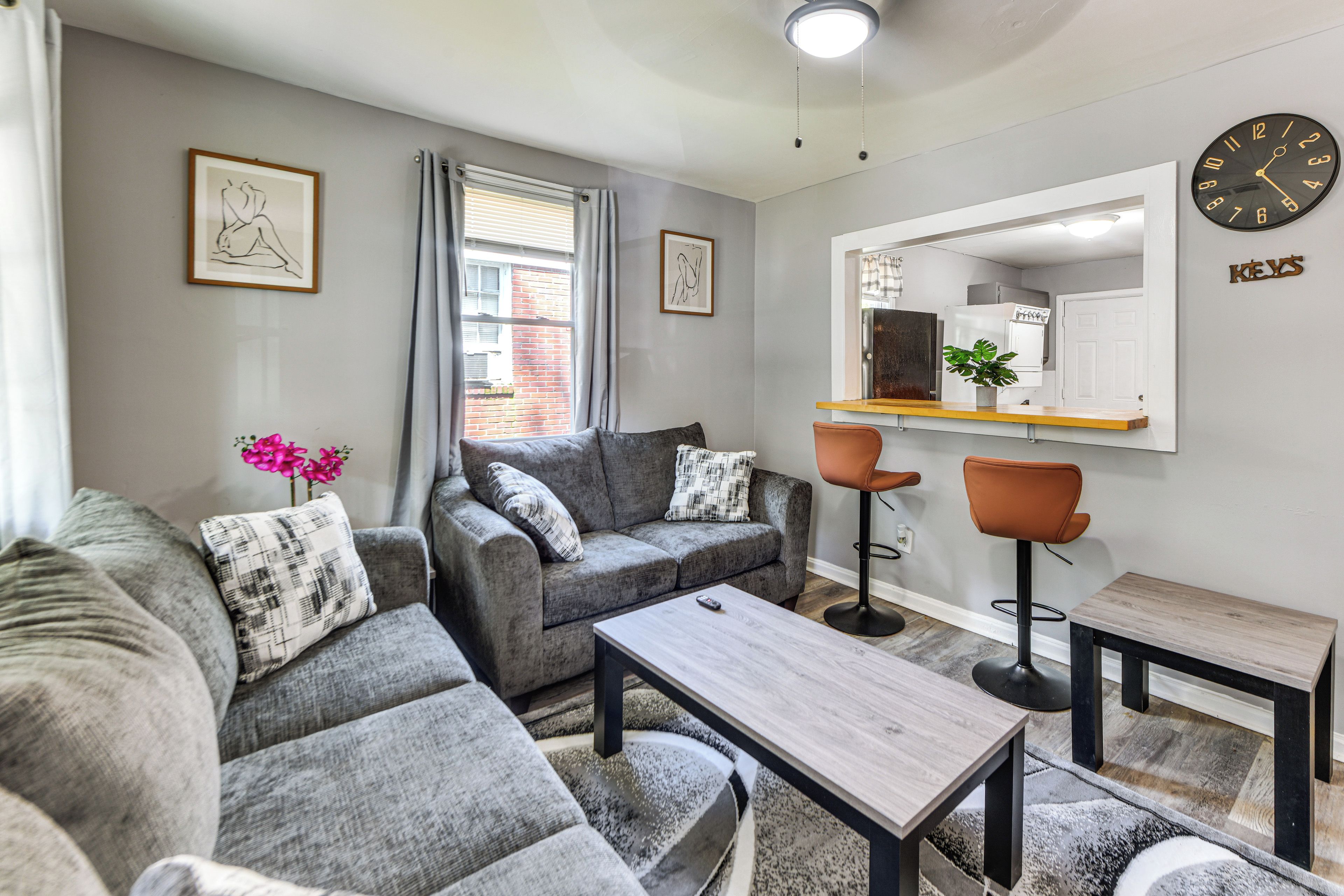 A modern living room with grey sofas, a wooden coffee table, and a bar area with stools.