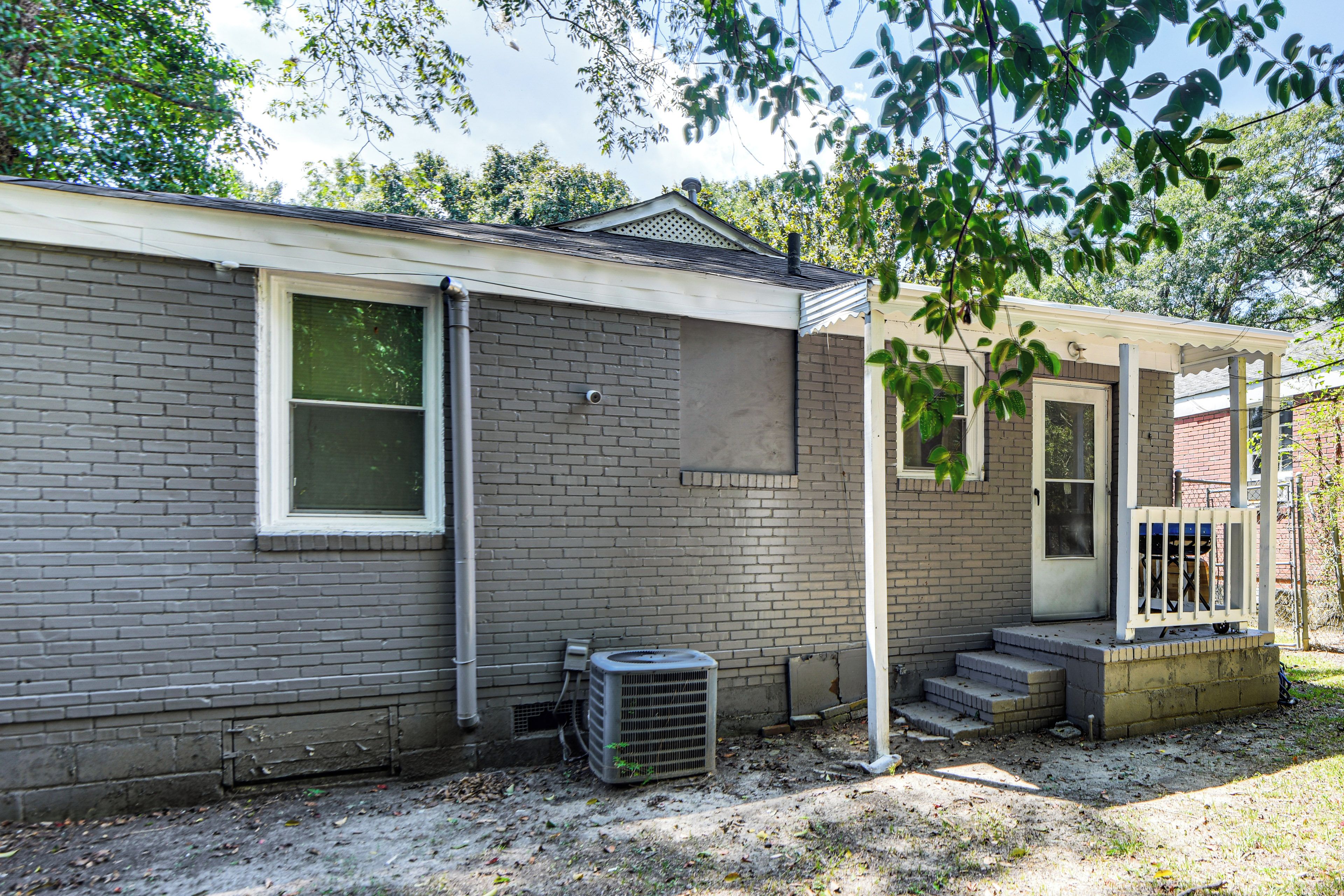 A single-story brick house with a small porch, a window, and a door.