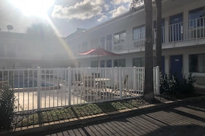 A courtyard with a white fence, outdoor furniture, and a red umbrella. - 1 Full Bed | Premium,Micfridge (Jacksonville)