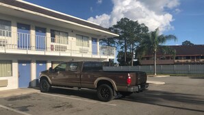 Una camioneta pickup marrón estacionada en un estacionamiento, con un edificio al fondo.