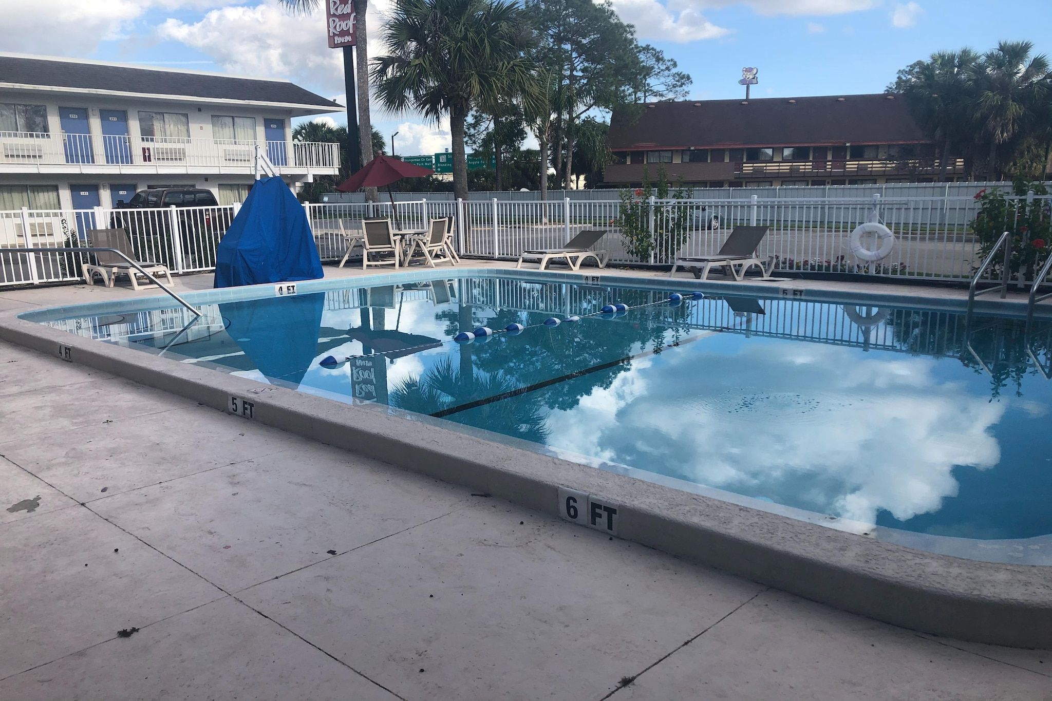 A swimming pool with a diving board and lounge chairs.