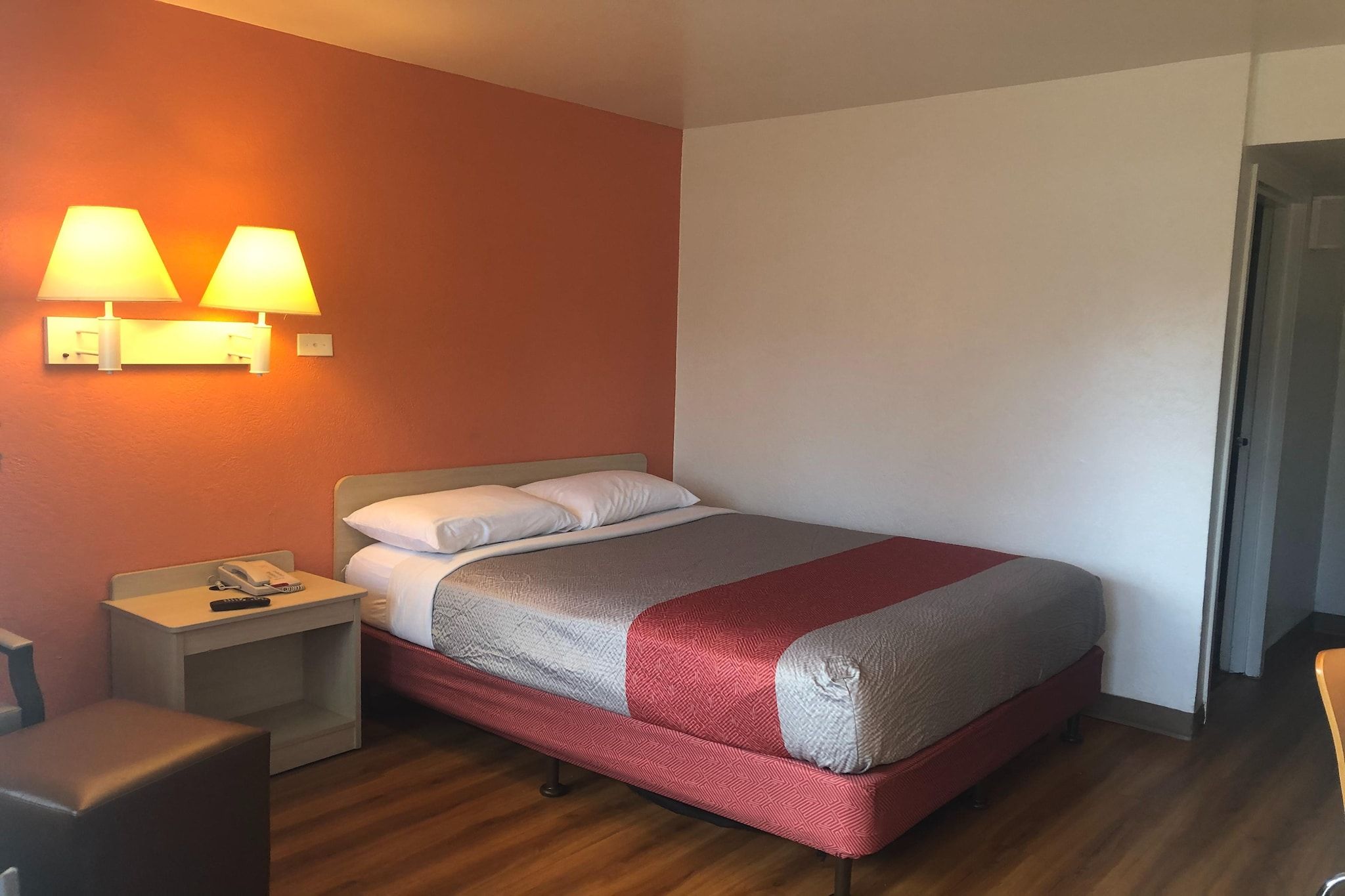 A hotel room with a bed, bedside tables, a telephone, and wall-mounted lamps.