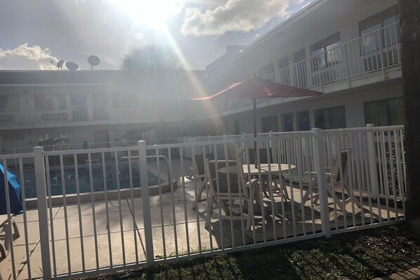 Un pati amb piscina, mobiliari exterior i una tanca blanca.
