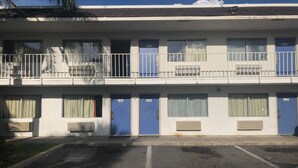 Um motel de vários andares com portas azuis, quartos numerados e estacionamento.