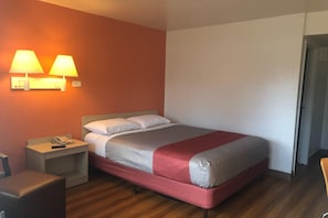 A hotel room with a bed, bedside tables, a telephone, and wall-mounted lamps. - 1 Full Bed | ADA/Tub (Jacksonville)