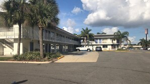 Motel amb un pàrquing, un camió blanc i una palmera.
