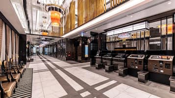 A spacious lobby with a check-in counter, seating area, and a chandelier.