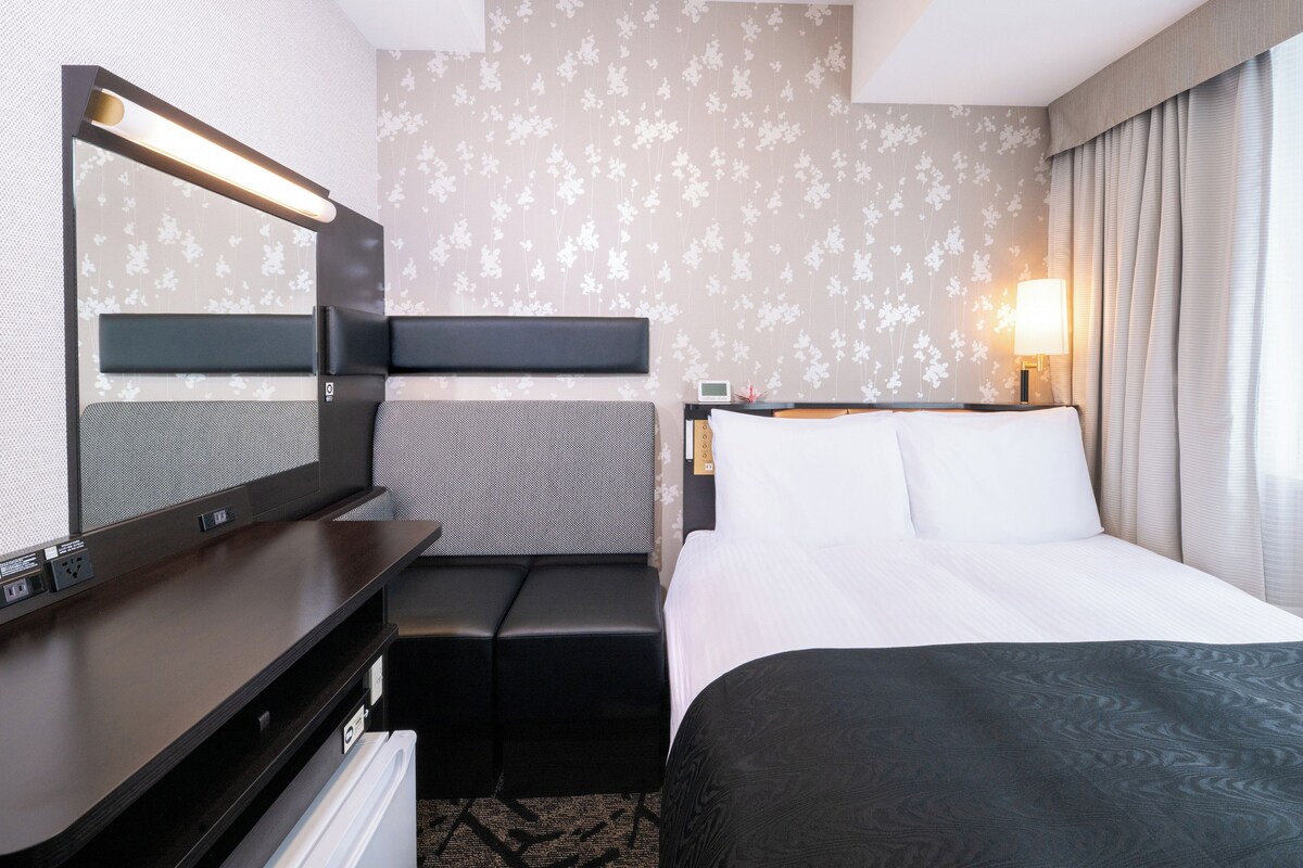 Ein Hotelzimmer mit Bett, Schreibtisch, Flachbildfernseher, Sitzecke und Wandlampe.