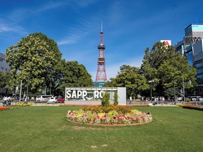 Ein Park mit einem markanten Turm und einem Schild, auf dem 'SAPPORO' steht.