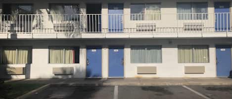 A multi-story motel with blue doors, numbered rooms, and a parking lot.