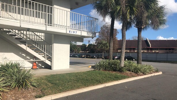 Un edificio con fachada blanca, un balcón y una escalera que sube a un nivel superior.