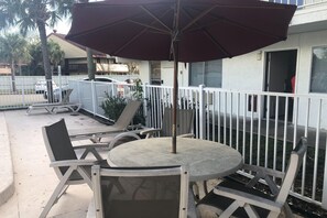 An outdoor seating area with a round table and chairs, a large umbrella, and a white fence. - Sunny 2-Bed Room|Pool|Free Wifi (Jacksonville)