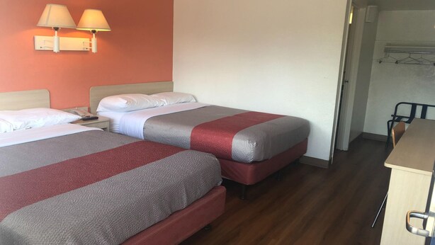 Habitació d'hotel amb dos llits, una tauleta de nit, una làmpada i un escriptori.