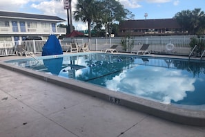 Une piscine avec un plongeoir et des chaises longues.