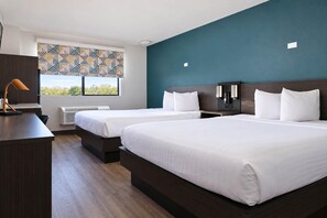 A hotel room with two beds, a desk, a lamp, and a window with a geometric pattern. - 2  Full Beds|ADA/Tub (Inglewood)