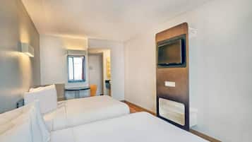 Een hotelkamer met twee bedden, een televisie en een raam.