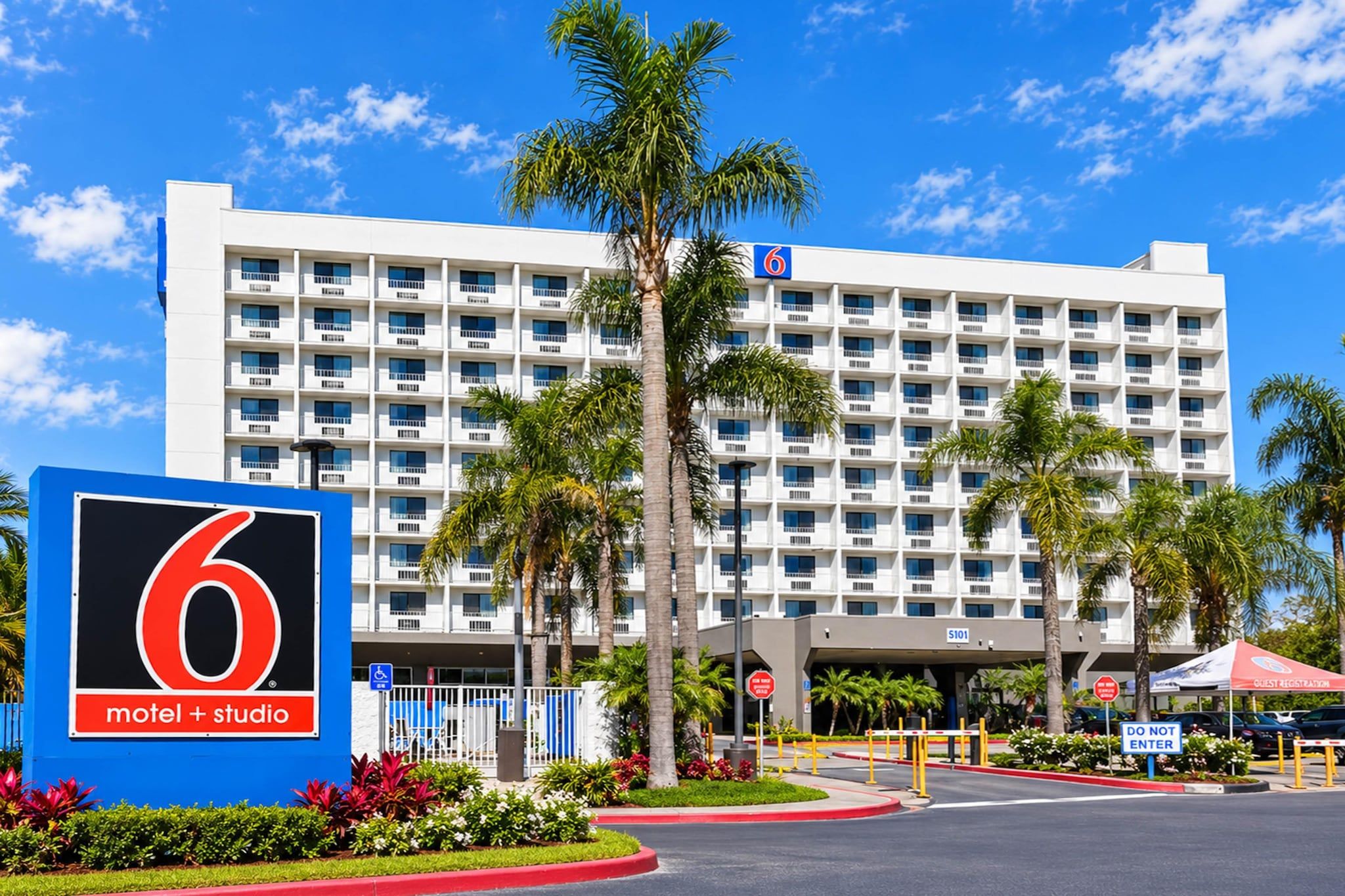 A 6 motel + studio building with a white facade, multiple balconies, and palm trees in the foreground.