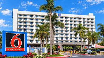 A 6 motel + studio building with a white facade, multiple balconies, and palm trees in the foreground.