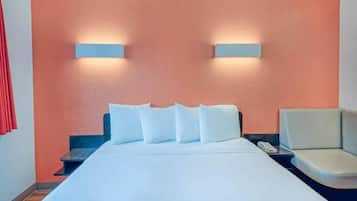 A hotel room with a bed, a nightstand, a chair, and two wall-mounted lights.