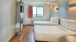 Camera d'albergo con due letti, una finestra con tende, una TV a schermo piatto e un lampadario a parete.