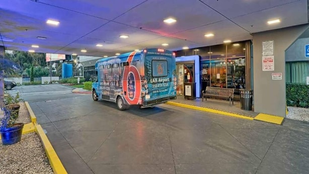 Un autobus parcheggiato all'ingresso di un terminal con un cartello che indica l'aeroporto LAX.